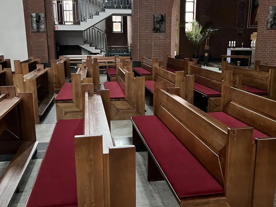Drewniane ławki kościelne z bordowymi siedziskami