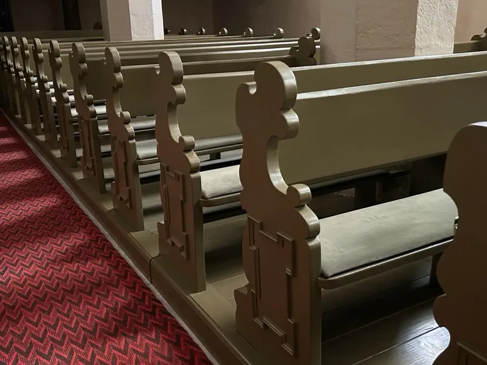 Rząd szarych siedzisk w ozdobnych ławkach kościelnych