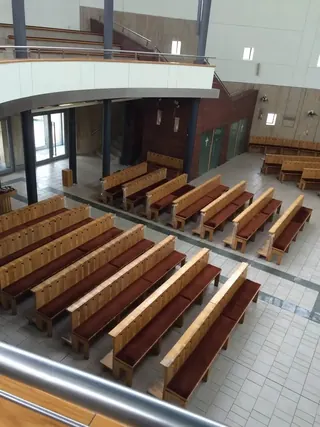 Widok z balkonu na rzędy ławek z bordowymi siedziskami