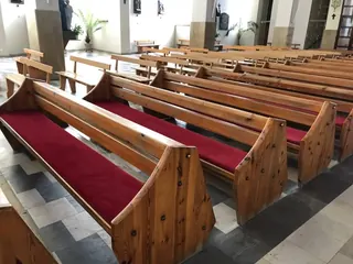 Sosnowe ławki kościelne z czerwonymi siedziskami i klęcznikami