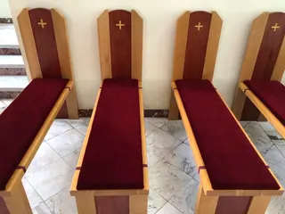 Indywidualne klęczniki z bordowym obiciem i krzyżami na oparciach