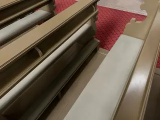 Jasne, tapicerowane siedziska zamontowane w ciemnych ławkach kościelnych