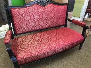Rzeźbiona sofa w czerwoną, wzorzystą tkaninę