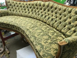 Gięta sofa w zieloną, wzorzystą tkaninę